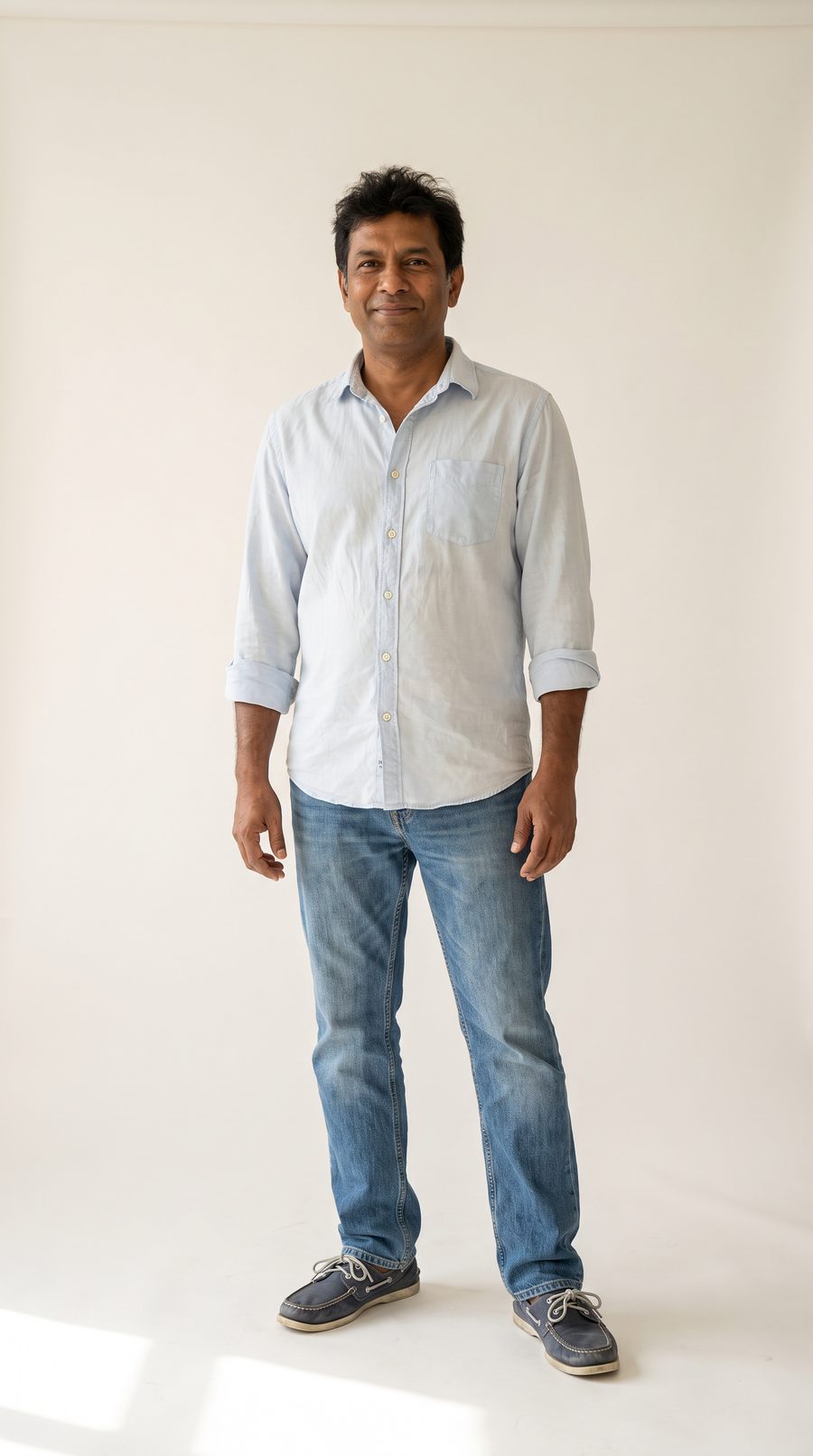Full length: pale blue formal shirt worn untucked, mid-wash jeans, boat shoes, short unshaped hair